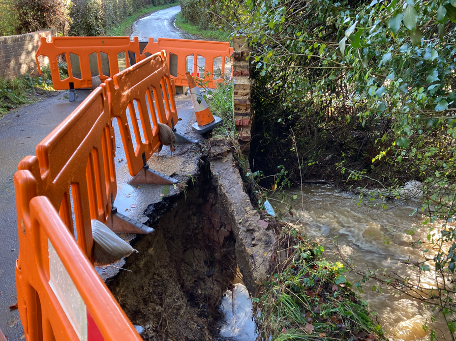 An image showing the damage caused by flood water, a large portion of the bridge and road surface missing and barriers making the area safe